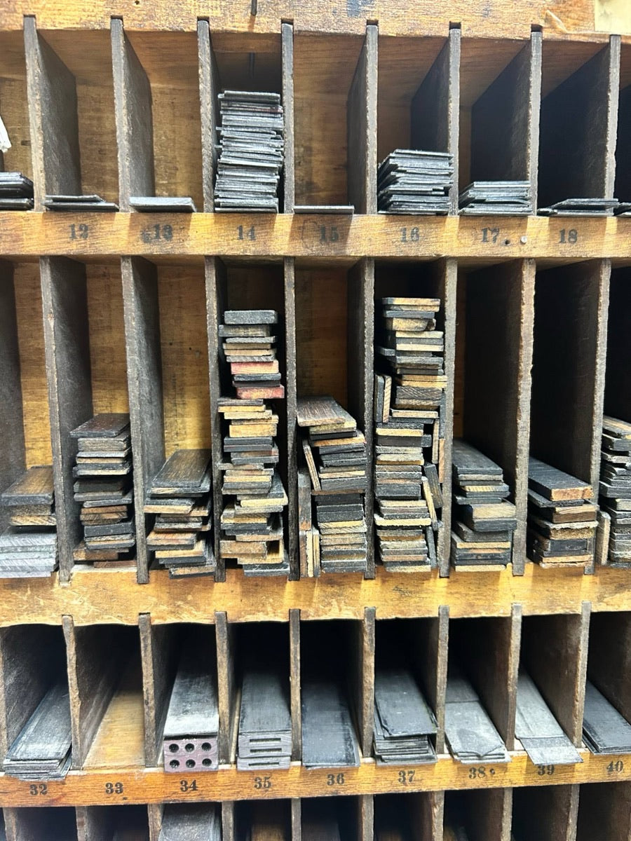 Numbered pigeonholes of a furniture cabinet, stacked with the wooden and metal spacing blocks used to lock up type